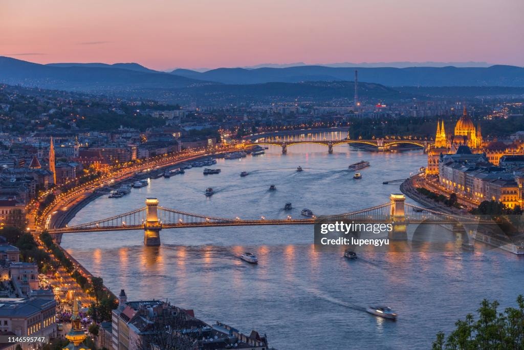 Budapest at dusk with illuminated bridges and river cruise ships